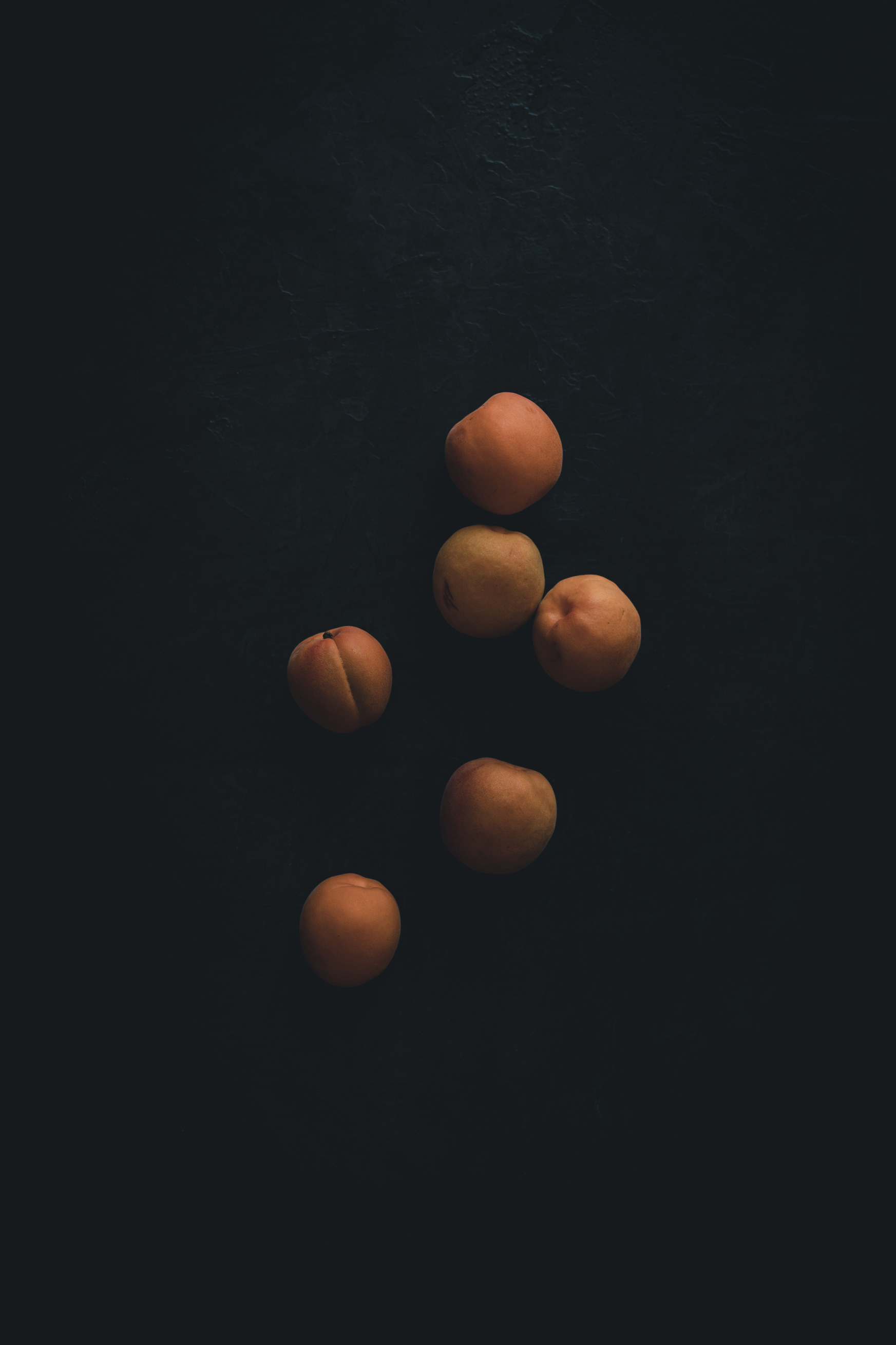 Apricots on a black background from the Moody Food series by John Robson Photography
