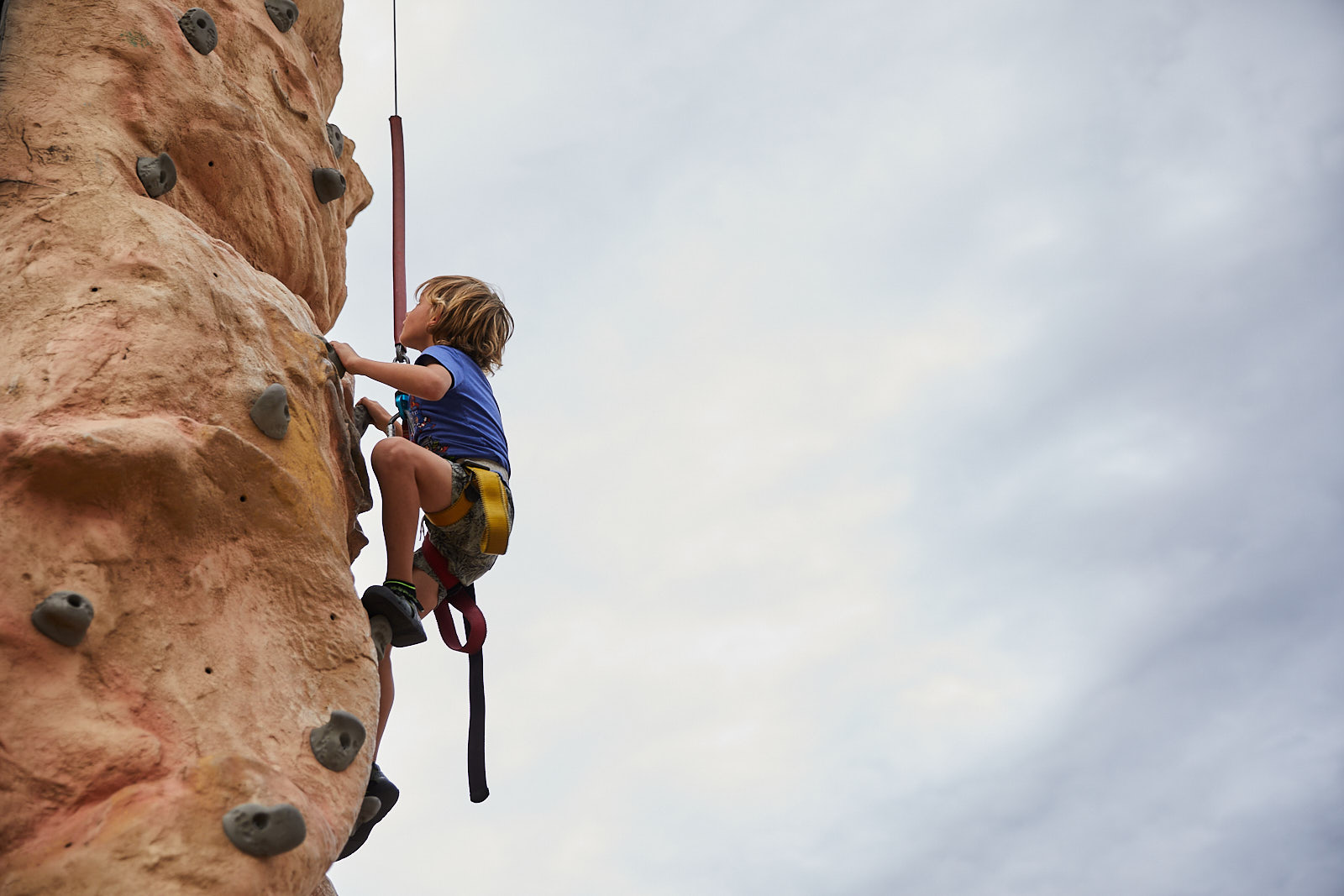 Young boy on a climbing wall at a festival in Longmont, Colorado - John Robson Lifestyle Photography