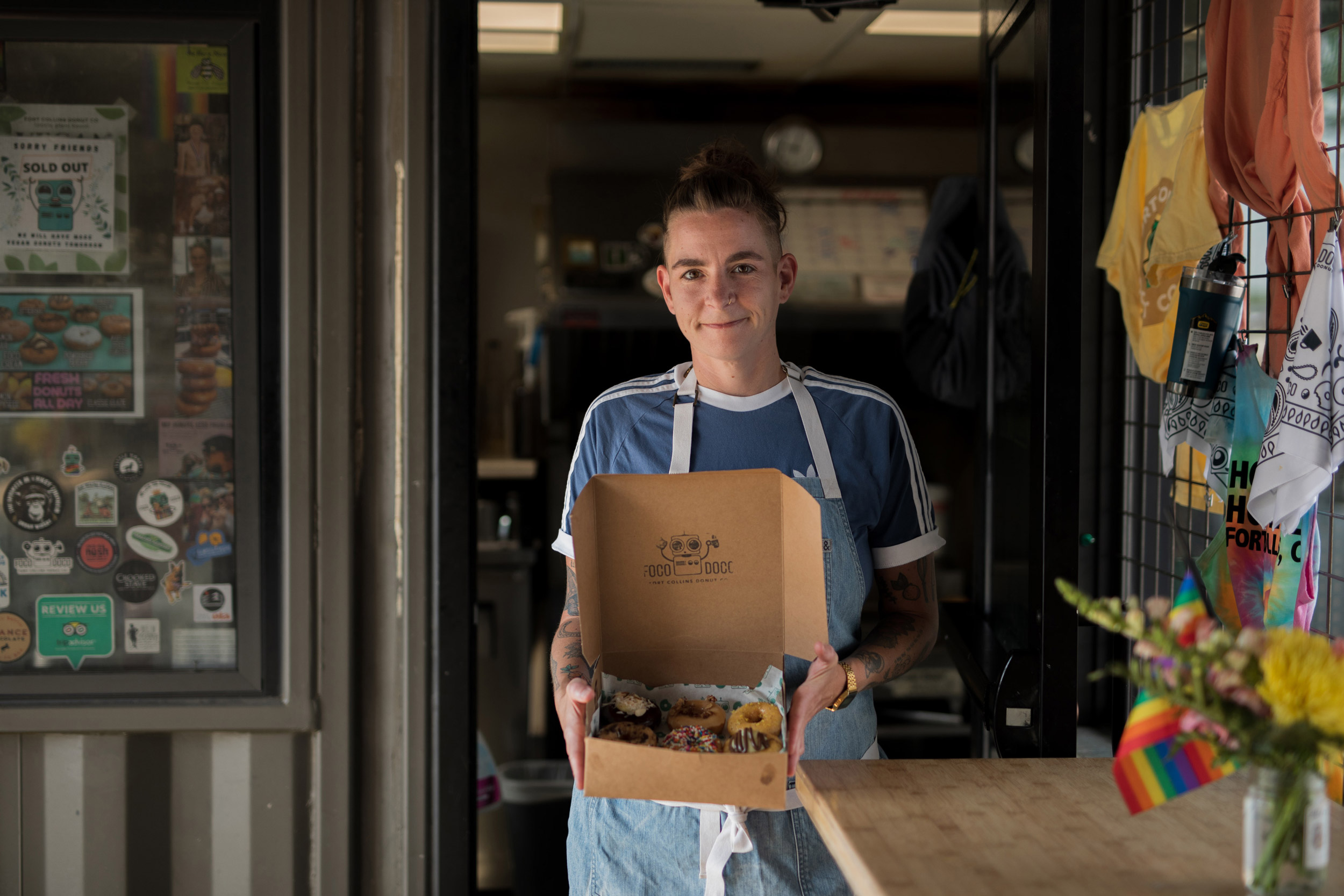 Lifestyle portrait of a doughnut shop owner holding doughnuts in Fort Collins, Colorado - John Robson Photography
