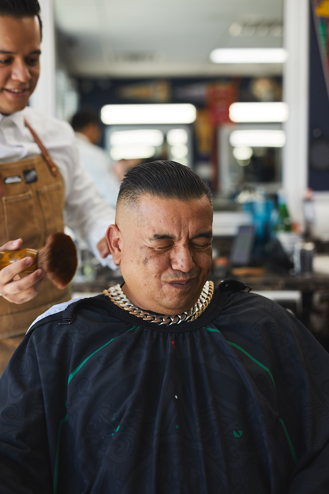 Man wincing while having hair brushed off at a barber shop in Fort Collins, Colorado - John Robson Photography