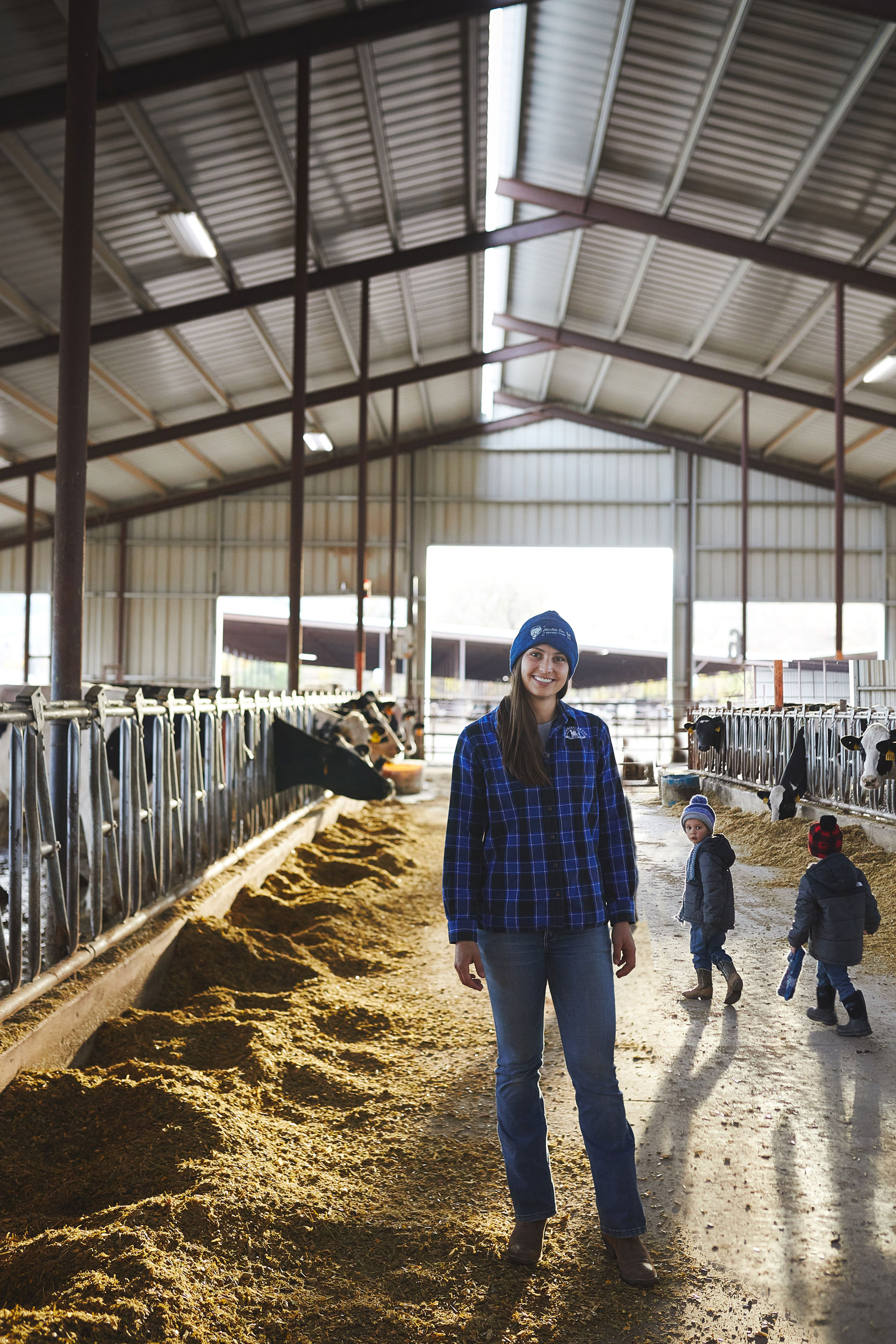 Woman standing in the dairy cow barn at Morning Fresh Dairy in Fort Collins, Colorado for Edible Magazine Denver - John Robson Editorial Photography