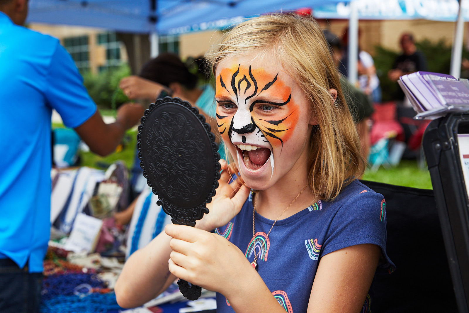 Young girl with a painted tiger face roaring in a mirror - John Robson Photography