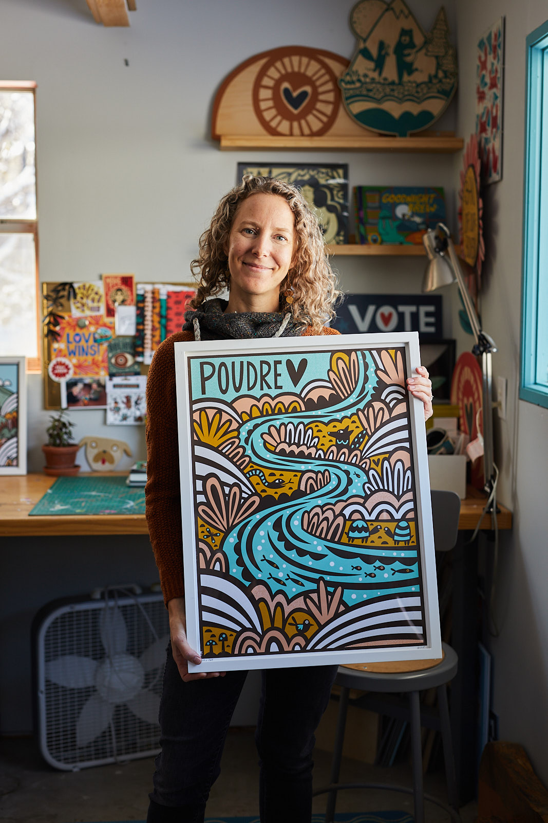 Portrait of an artist holding her illustration in her studio in Fort Collins, Colorado - John Robson Photography