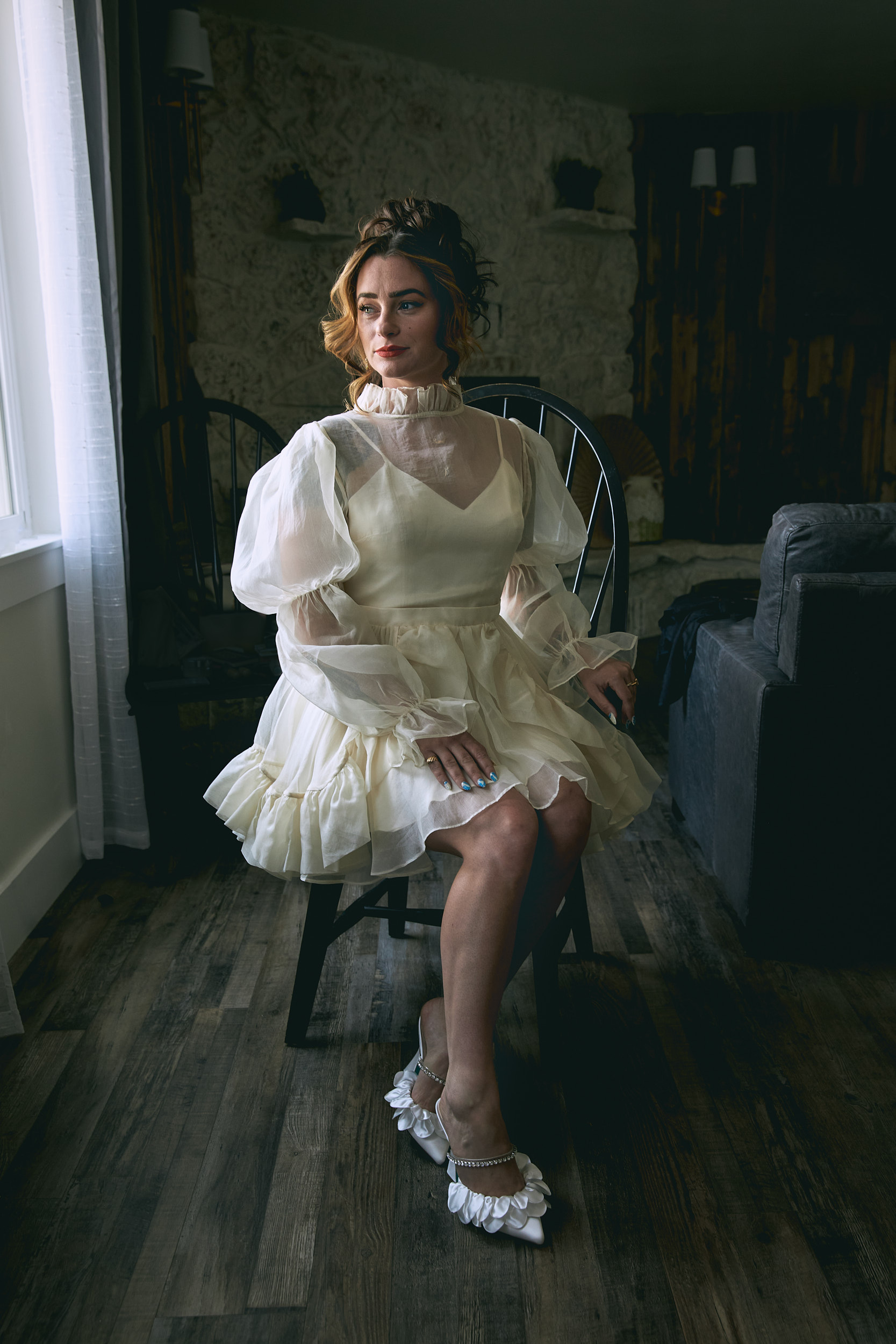 Portrait of a bride siting on a chair looking out the window in Palisade, Colorado - John Robson Photography