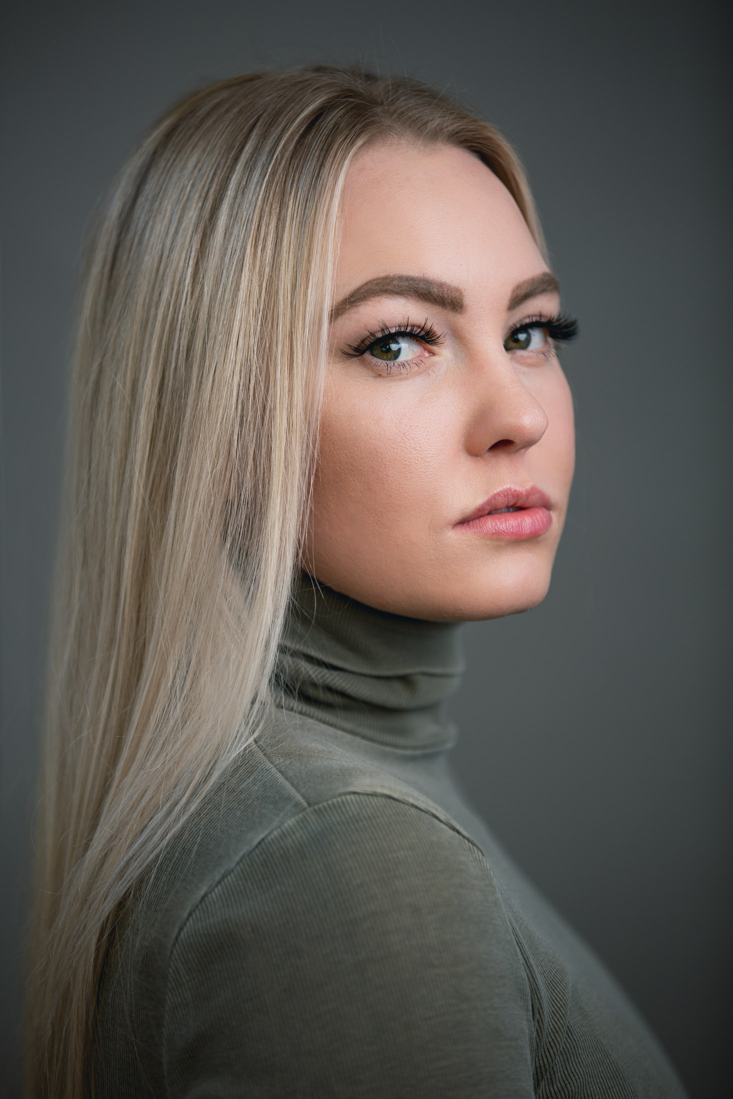 Side portrait of a young blonde woman in a green turtleneck - John Robson Photography