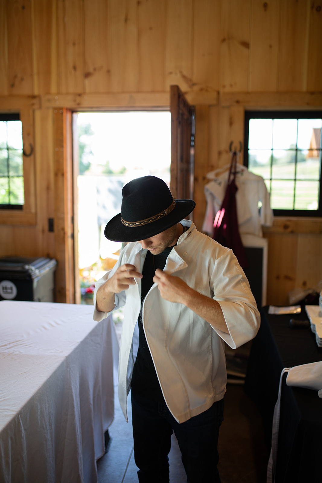 Chef with wide brimmed hat putting on his whites prior to service - John Robson Photography