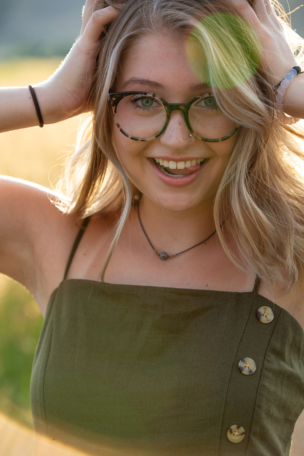 Senior portrait of a young woman playing with her hair and sticking out her tongue in Fort Collins, Colorado - John Robson Photography